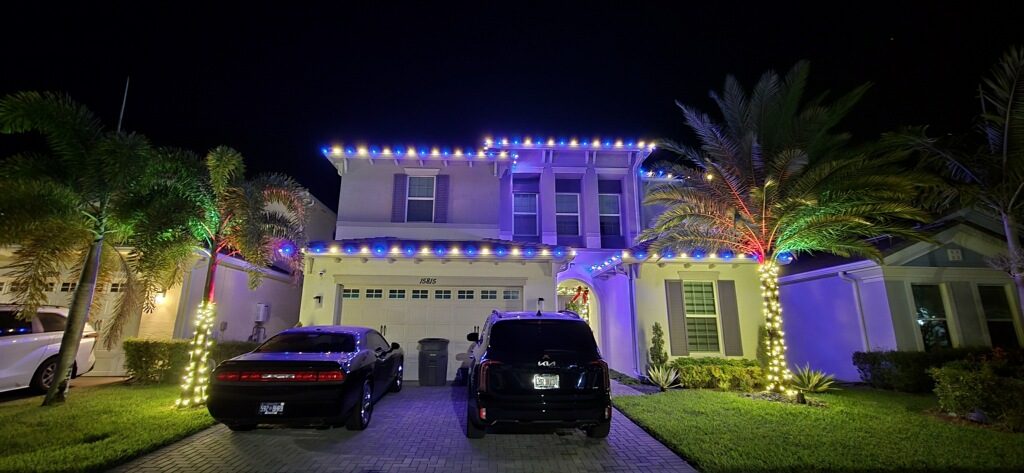 Twilight view of a home with wrapped palms glowing for the holidays
